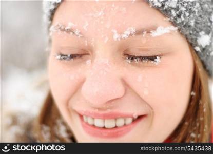 Girl&rsquo;s face with closed eyes under snow outdoors. Close up portrait