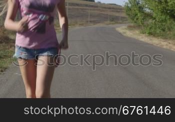 Girl running along a country road in summer