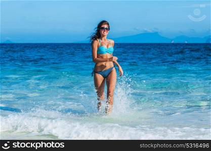 Girl running from sea. Beautiful happy girl running in tropical sea waves