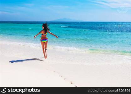 Girl running near sea. Beautiful happy girl running in tropical sea waves