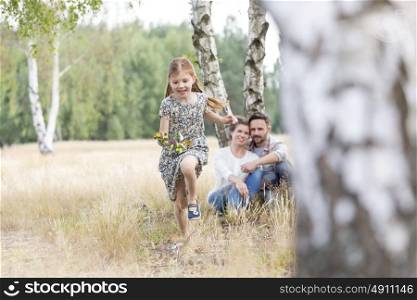 Girl running on field while parents sitting at farmland