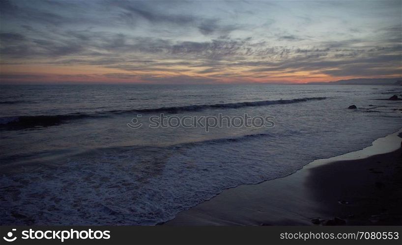 Girl runs along Mesa beach at Sunset