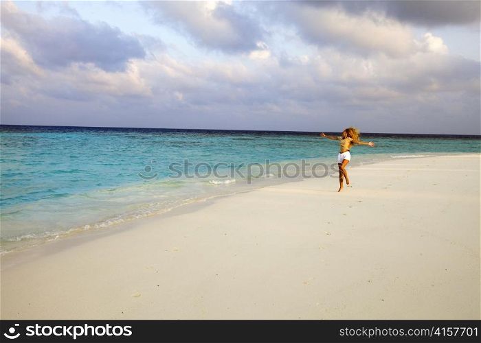 Girl runs at sunset along strip of surf