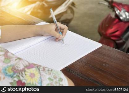 girl's hand holding pen writing on notebook