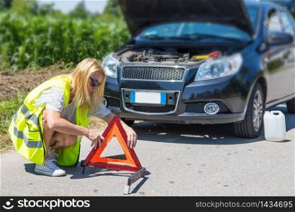 girl sets a triangle in front of broken car