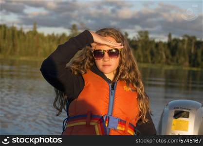 Girl shielding eyes from the sunlight, Lake of The Woods, Ontario, Canada