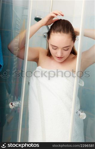 Girl showering in shower cabin cubicle enclosure. Young woman with white towel taking care of hygiene in bathroom.. Woman showering in shower cabin cubicle.