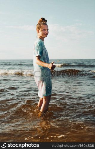 Girl showing okay gesture standing in a water spending a free time over a sea during summer vacation at sunset. Girl showing okay gesture standing in a water spending a free time over a sea during summer vacation