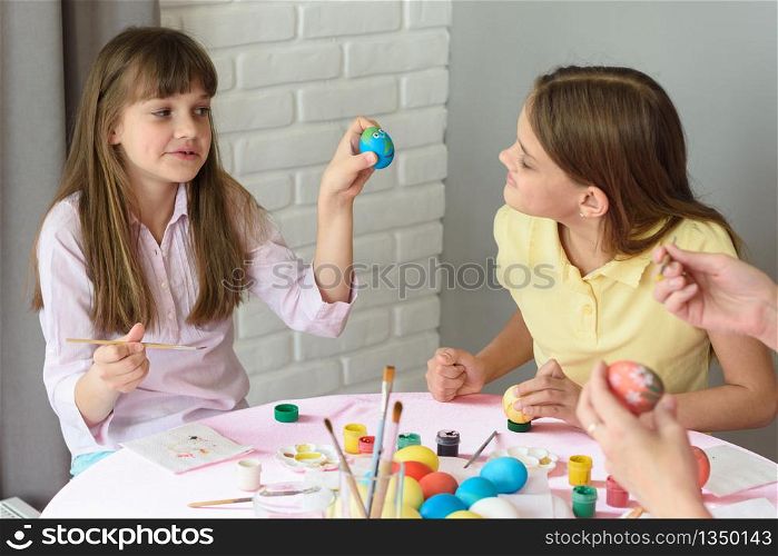 Girl shows sister how she painted an Easter egg