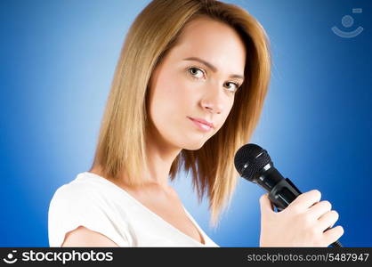 Girl singing with microphone against gradient background