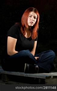 Girl siting on wood, flash lighting, redhead. Lit with two offcamera flashes.