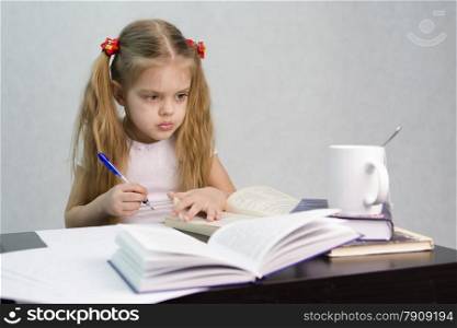 girl sits at a table and flips through the book and writes out the information you need. Next are still books, sheets of paper, a pen, a glass of tea. The image of a student, a pupil, a teacher and literary critic