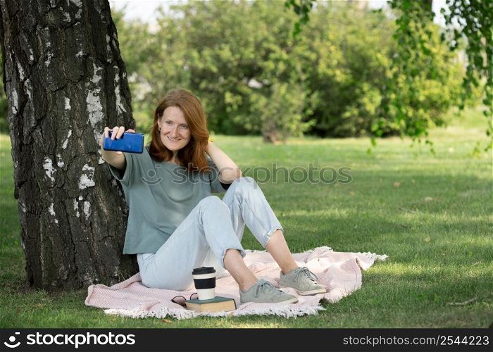 girl sits on the lawn and takes a selfie on the phone