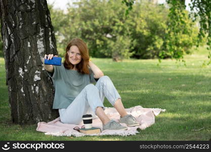 girl sits on the lawn and takes a selfie on the phone