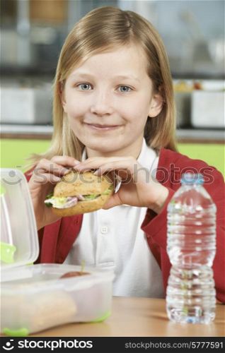 Girl Sitting At Table In School Cafeteria Eating Healthy Packed Lunch