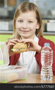 Girl Sitting At Table In School Cafeteria Eating Healthy Packed Lunch