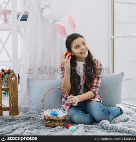 girl sitting bed listening noise from red easter s egg