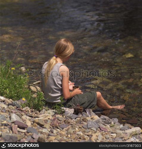 Girl sitting by stream