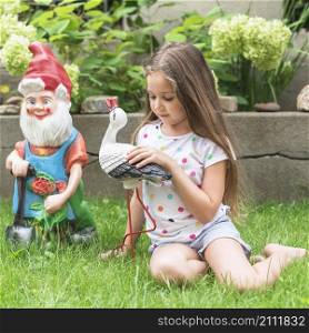 girl sitting green grass playing with statue