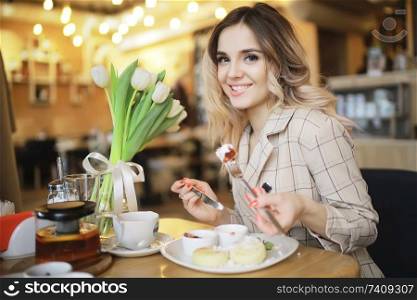 girl sitting in a cafe at a table / beautiful young model posing with a bunch of flowers, happy adult girlfriend