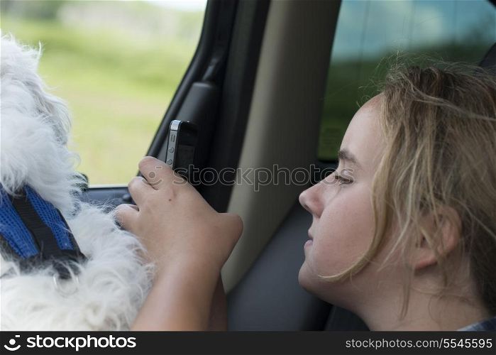 Girl sitting in a car using a mobile phone, Lake Audy Campground, Riding Mountain National Park, Manitoba, Canada