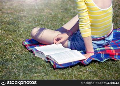 girl sitting in a meadow near the river and reading a book