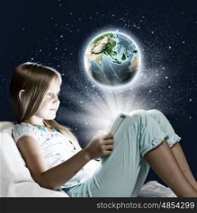 Girl sitting in bed and playing with tablet pc. Elements of this image are furnished by NASA