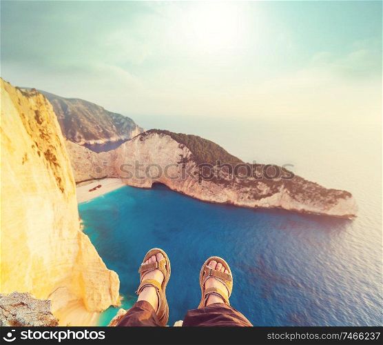 Girl sitting on a high cliff above sea. Travel concept.