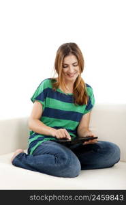 Girl sitting on a sofa and using a tablet, isolated on white background