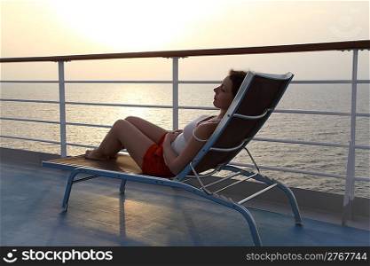 girl sitting on beach chair at ship deck side view full body