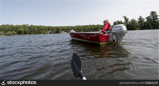 Girl sitting on motorboat in a lake, Lake of the Woods, Ontario, Canada