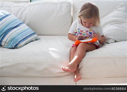 Girl sitting on sofa using handheld video game
