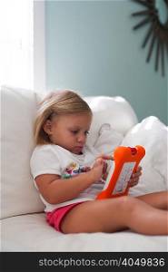 Girl sitting on sofa using handheld video game