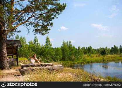 girl sitting on the shore of the lake and reading a book, Ukrainian landscape