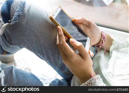 girl sitting on the windowsill with smartphone