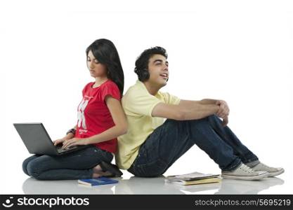 Girl sitting with a laptop while boy listens to music