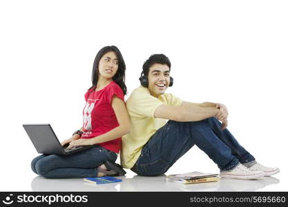 Girl sitting with a laptop while boy listens to music