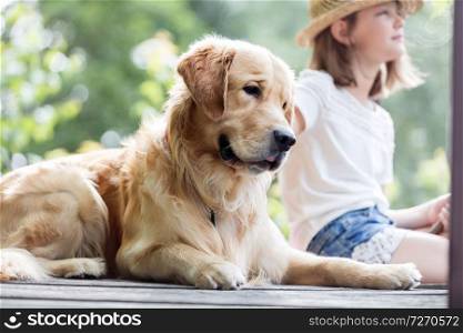 Girl sitting with Golden retriever dog on pier