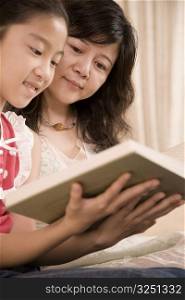 Girl sitting with her mother and reading a book