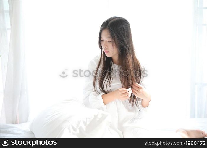 girl sitting with pillow at white bedroom