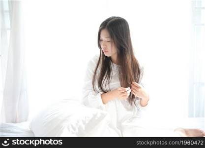 girl sitting with pillow at white bedroom