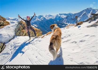 Girl ski touring in the mountains with dog is happy