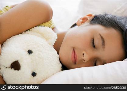 Girl sleeping on bed with teddy bear head and shoulders