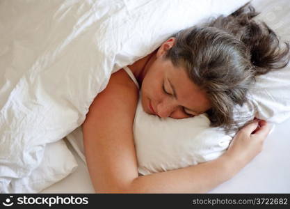 girl sleeping on his stomach hugging pillow