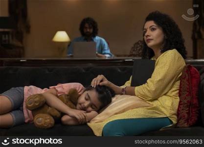 Girl sleeping on sofa while her mother looking away with holding a book and father using laptop