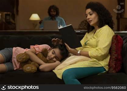 Girl sleeping on sofa while her mother reading book and father using laptop