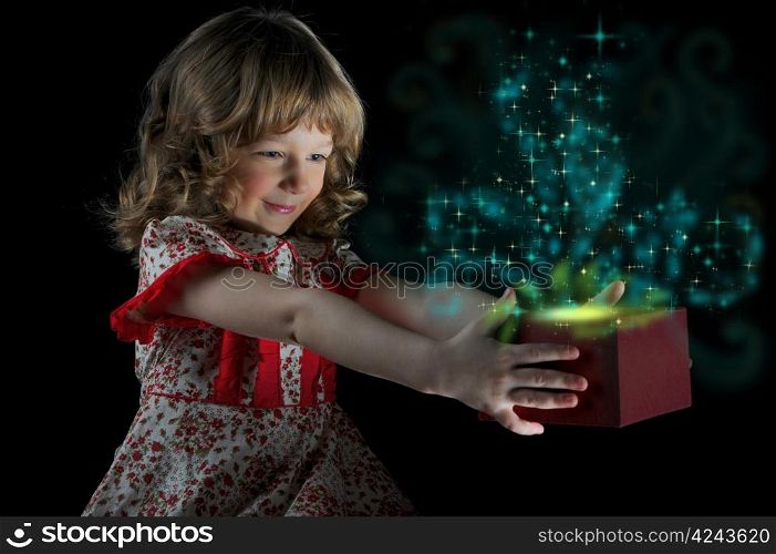 Girl smiles and holding a gift in magic packing on a black background