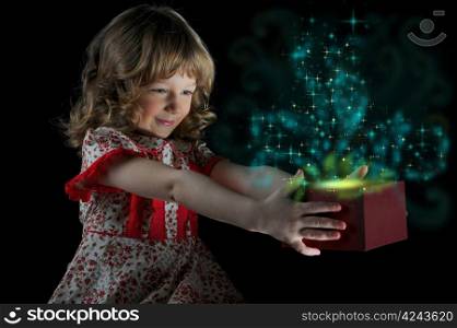 Girl smiles and holding a gift in magic packing on a black background