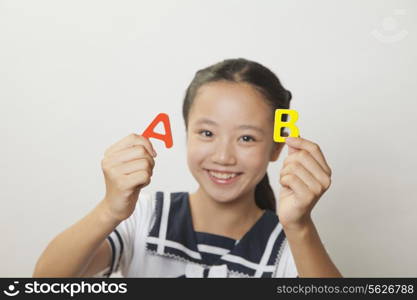 Girl smiling and holding plastic letters, Studio