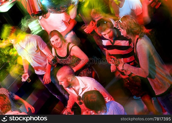 Girl smiling at the camera on a crowdy dance floor in a discotheque